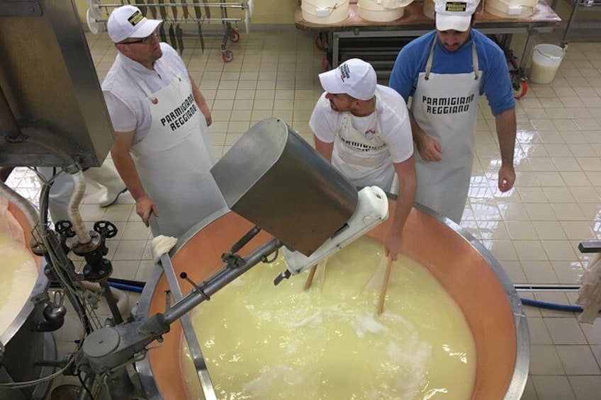 Three people in a kitchen, one pouring a liquid into a large pot. 3