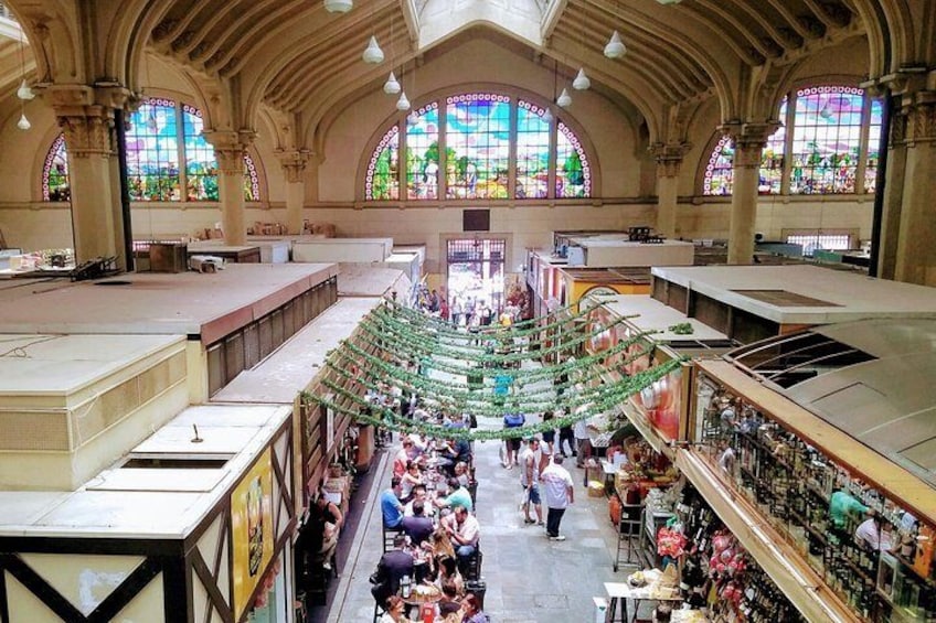 Un vaste marché couvert doté d’un escalier central, entouré de stands et de clients. 1