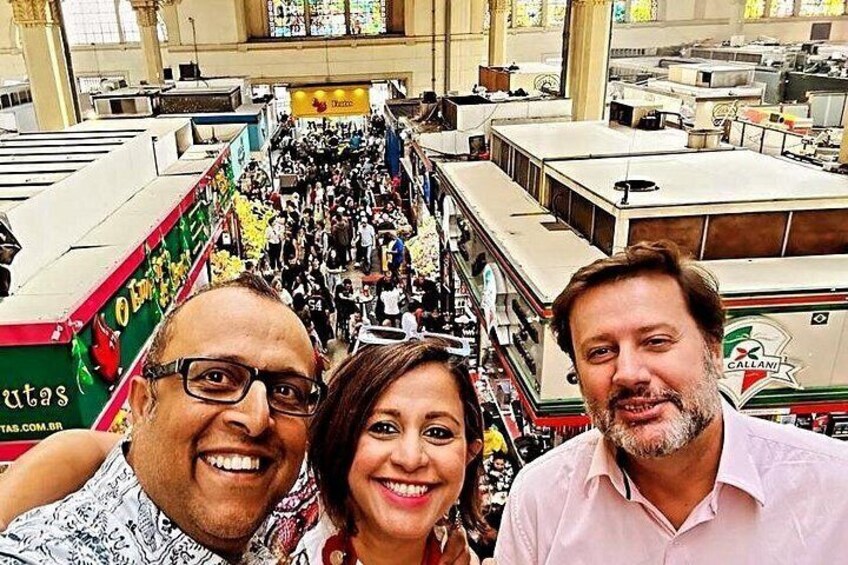 A crowded indoor market with people browsing and a large green truck in the background. 2