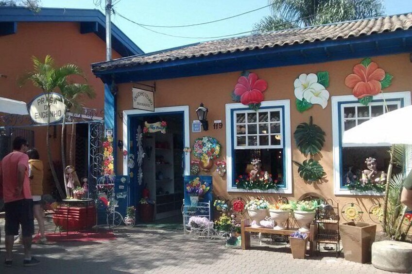 A colorful building with large flower decorations, a signboard, and various items displayed outside. 3