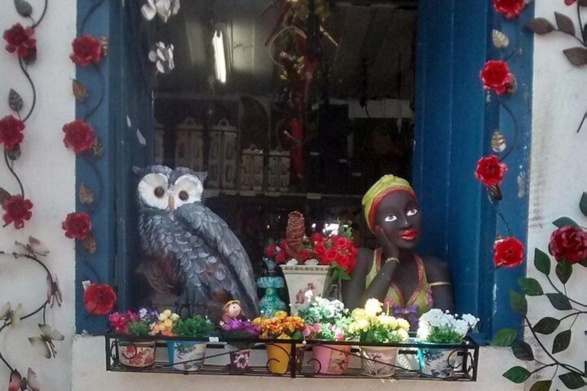 A storefront with a blue window frame, a decorative owl, and a mannequin dressed in a colorful outfit. 2