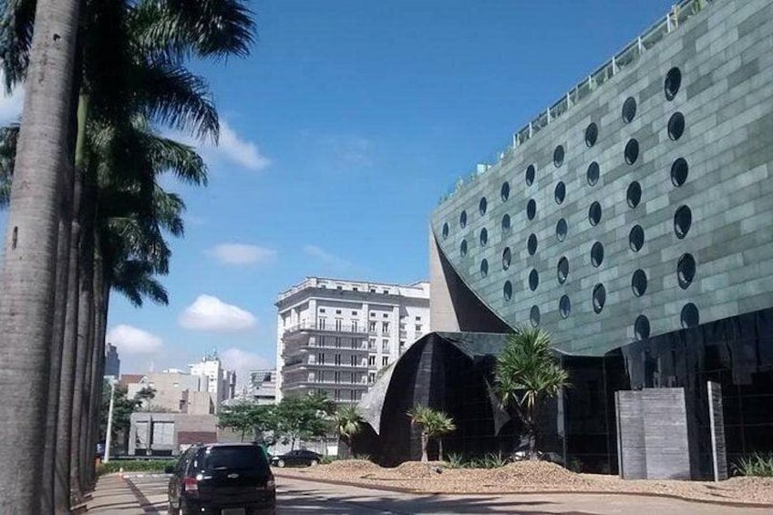 Un bâtiment moderne doté de fenêtres rondes, de palmiers et d’une voiture garée. 2