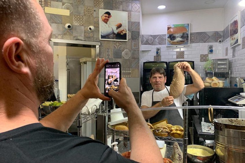 A person taking a photo of a food preparation area with a large hanging dough. 3