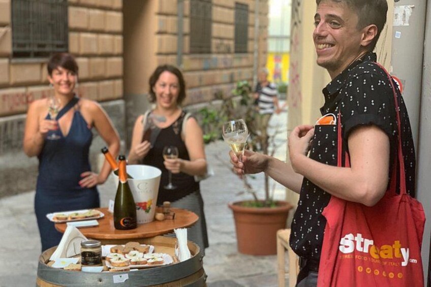 A person holding a glass of wine, a bottle of champagne, and a tray with food and a drink. 2