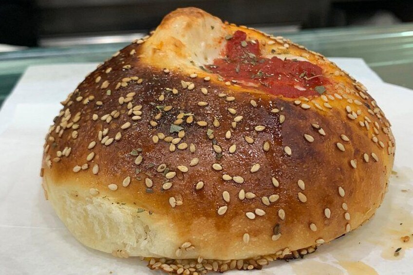 A sesame seed bun with a bite taken out, placed on a white surface. 2