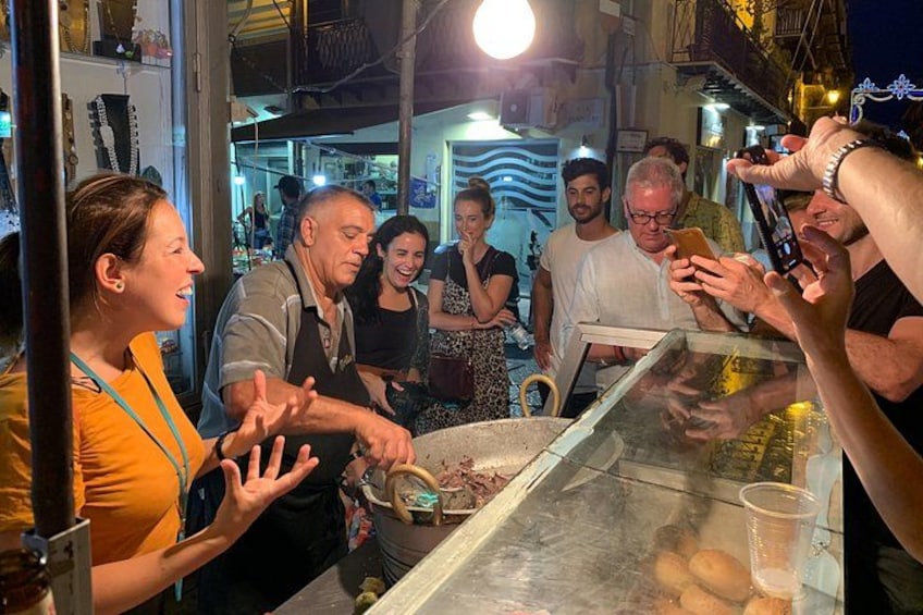 A group of people at a food stall with a person serving food. 1
