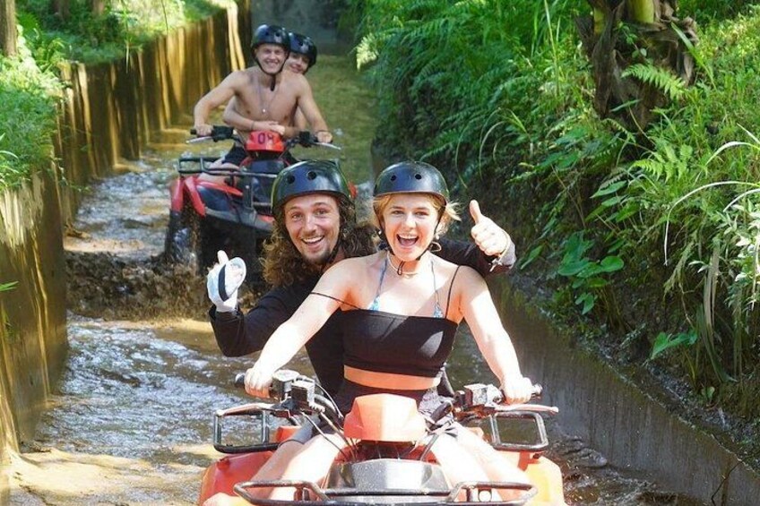 Two people on a quad bike, a narrow path, and greenery. 2