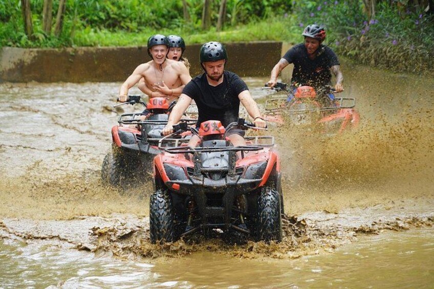 Mensen rijden met quadbikes door een modderige waterovergang. 3