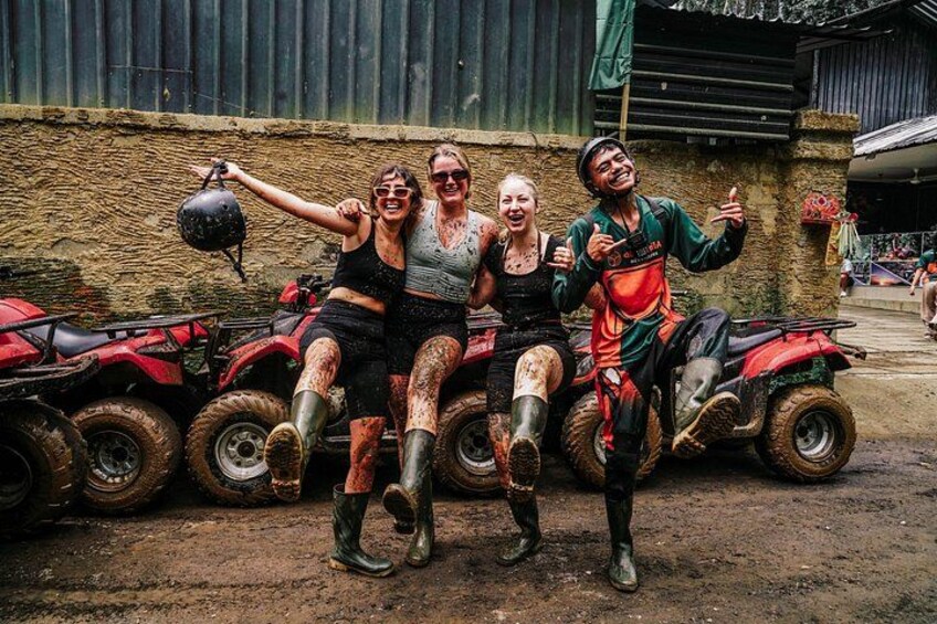 Three people on ATVs with mud on their clothing and vehicles, standing in front of a building with a dirt ground. 5