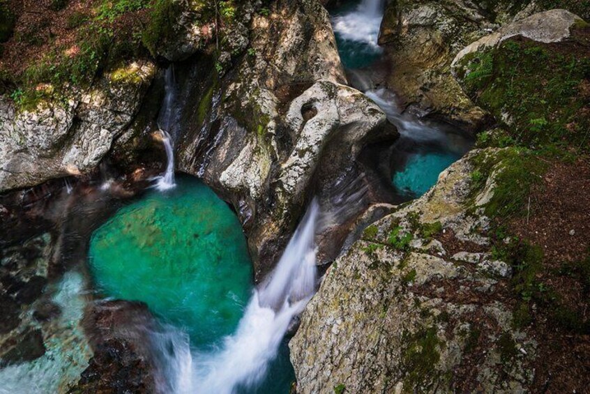 A turquoise pool surrounded by rocky terrain with a waterfall. 5