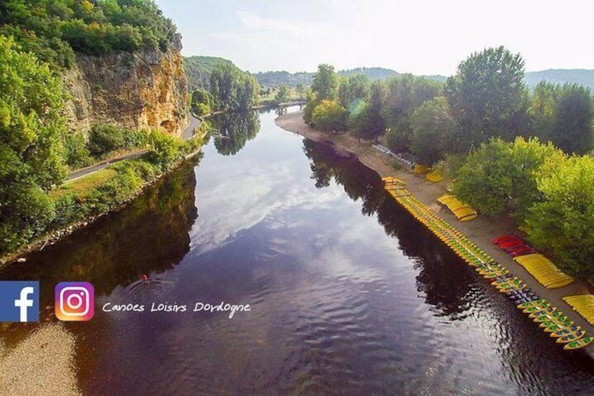 A calm river with boats lined up on the right bank, surrounded by greenery and cliffs. 3