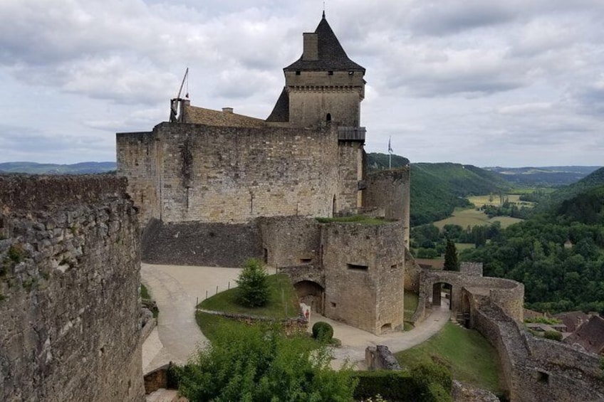 A medieval castle with a prominent tower, surrounded by lush green hills and a clear sky. 4