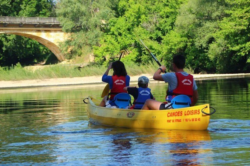 A yellow canoe with people wearing life jackets on a calm river. 2