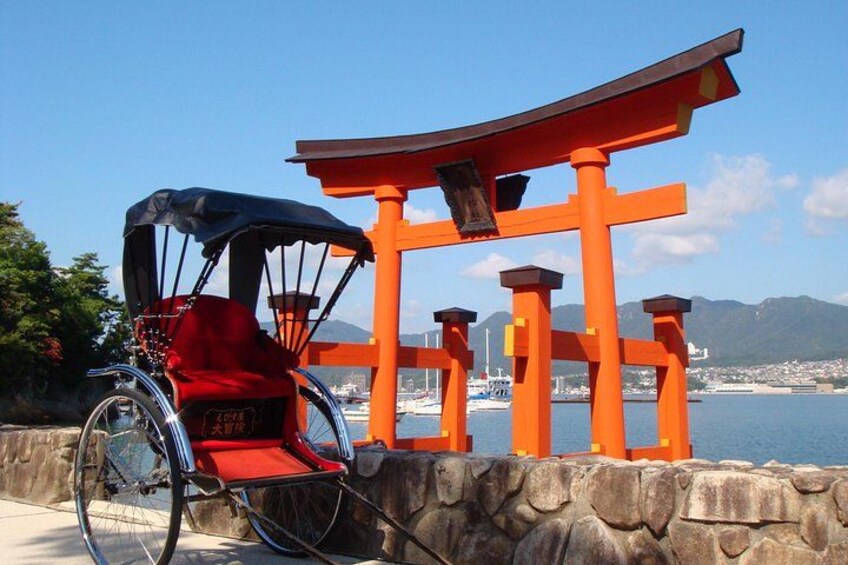 A wheelchair near a traditional Japanese torii gate with a clear view of the sea and mountains in the background. 1