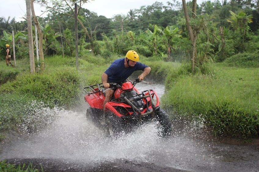 Una persona conduce un cuatrimoto rojo por un canal fluvial rodeado de follaje. 4