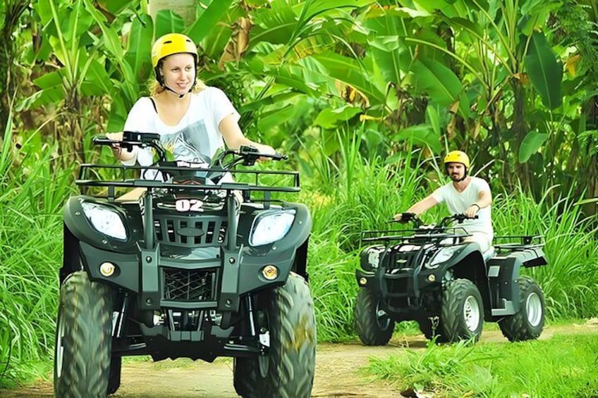 Two people riding ATVs on a dirt path surrounded by lush greenery. 5