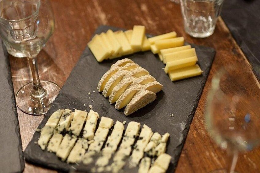 Un tagliere con diversi tipi di formaggio e un bicchiere di vino su un tavolo di legno. 5