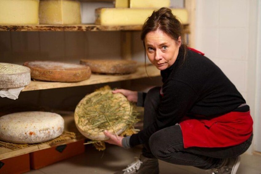 Une personne manipule une grande meule de fromage dans une salle d’affinage. 4