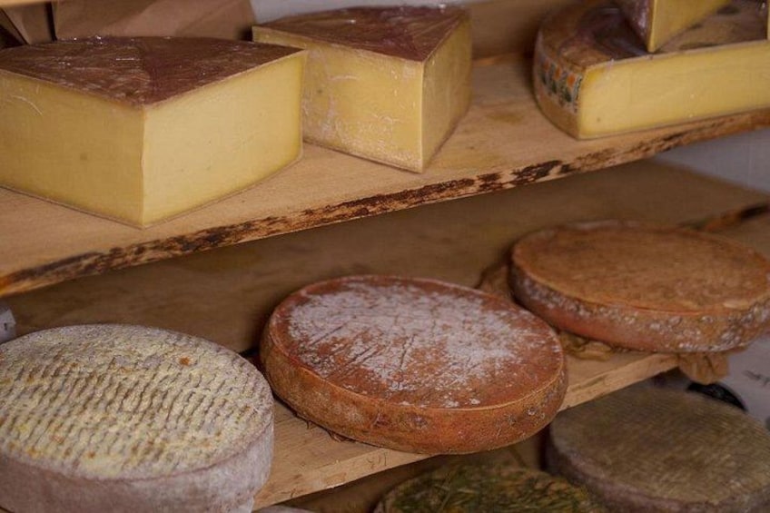Différents types de fromages présentés sur des étagères en bois. 1