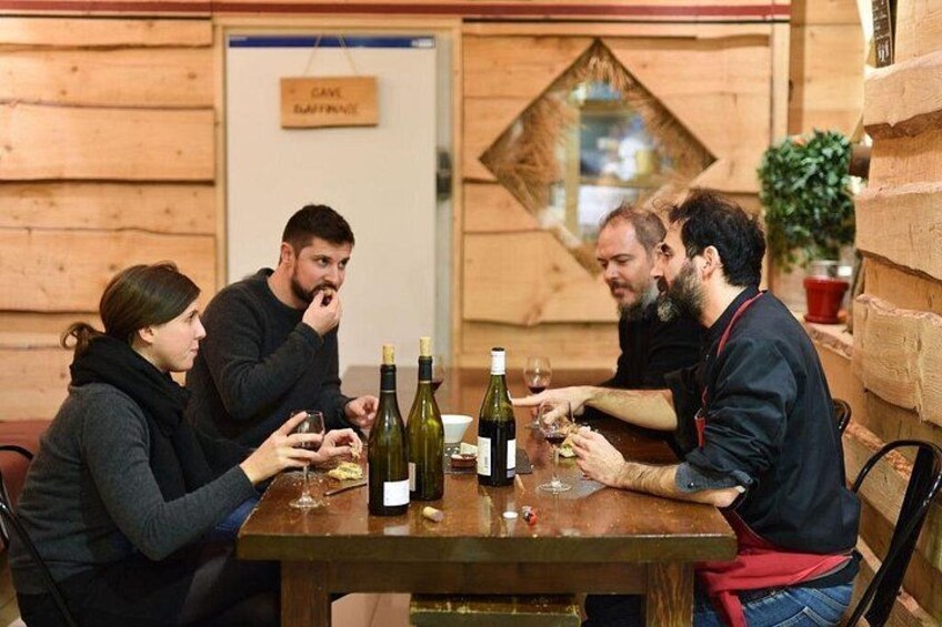 Un gruppo di persone sedute a un tavolo di legno con bottiglie e bicchieri di vino. 4