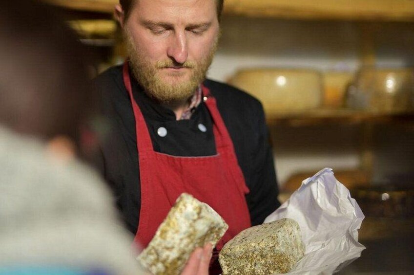 Een persoon in een rode schort, dat brood en een zak bloem vasthoudt. 4
