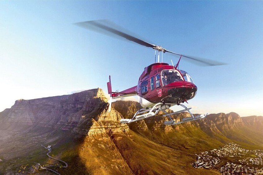 A red helicopter flying over a mountainous landscape with a clear sky. 3
