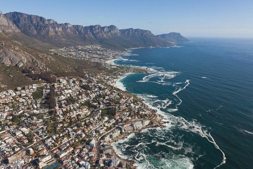 A coastal city with a rugged coastline, a dense urban area, and a mountain range in the background. 2