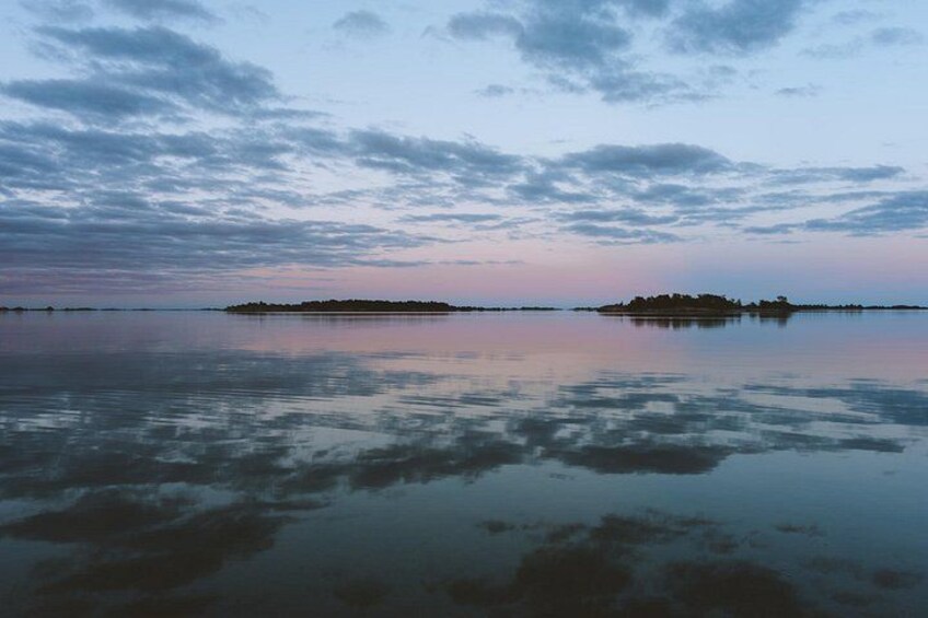 A calm lake with a small island in the distance, surrounded by a cloudy sky. 5