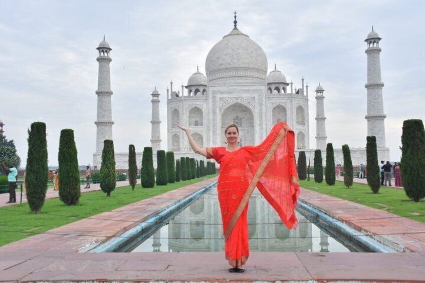 A person in a red saree standing in front of the Taj Mahal. 3