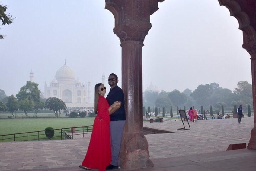 A couple standing in a Mughal architectural setting with the Taj Mahal in the background. 5