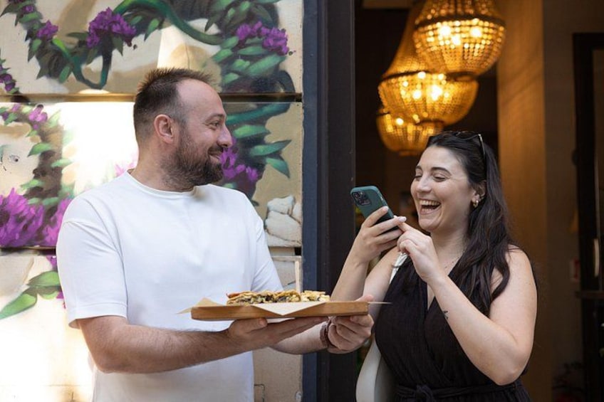 A person holding a pizza box and a smartphone. 5