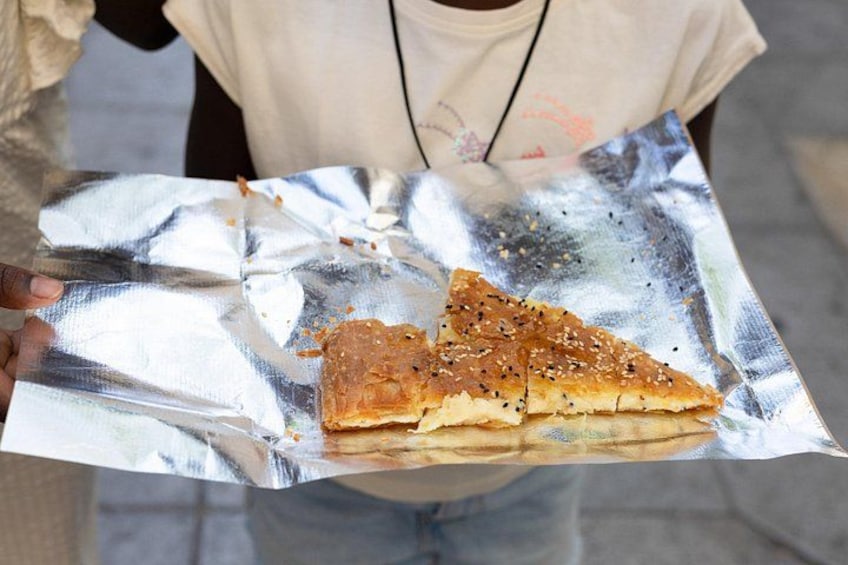 A person holding a piece of food on aluminum foil. 4