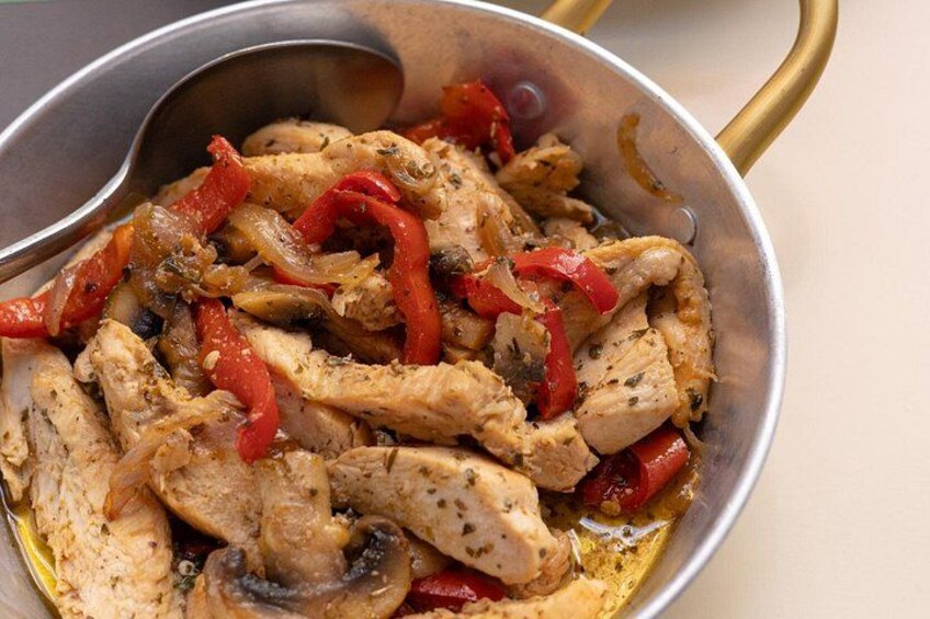 Una sartén con pollo cocido, pimientos rojos y cebollas. 3