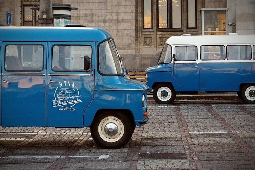 Un vieux fourgon bleu est garé sur une rue pavée, avec un bâtiment en arrière-plan. 2