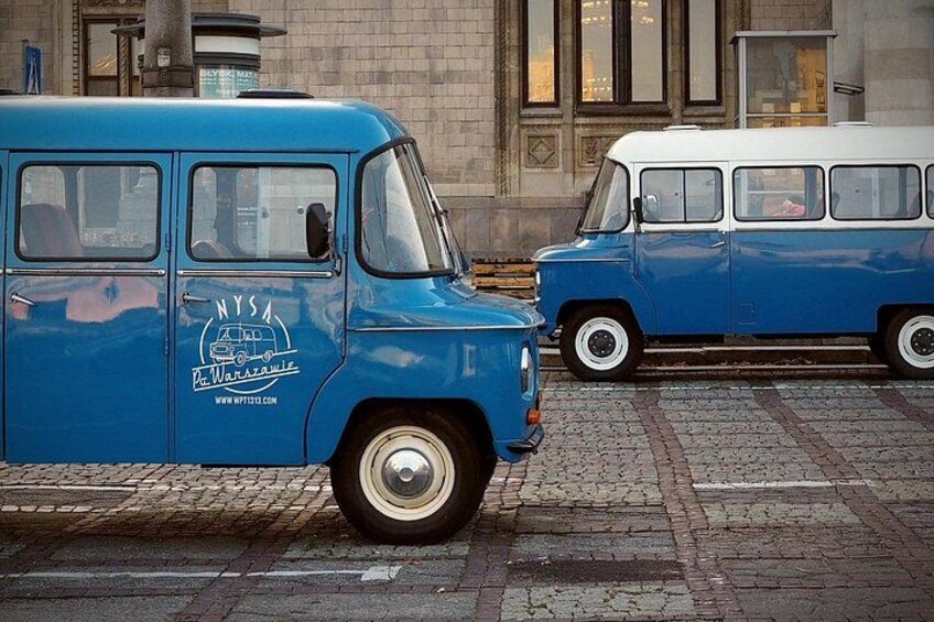 A blue vintage van parked on a cobblestone street. 2