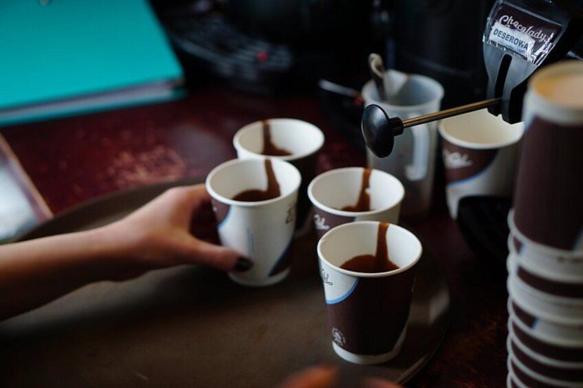 A person pouring coffee into paper cups. 3