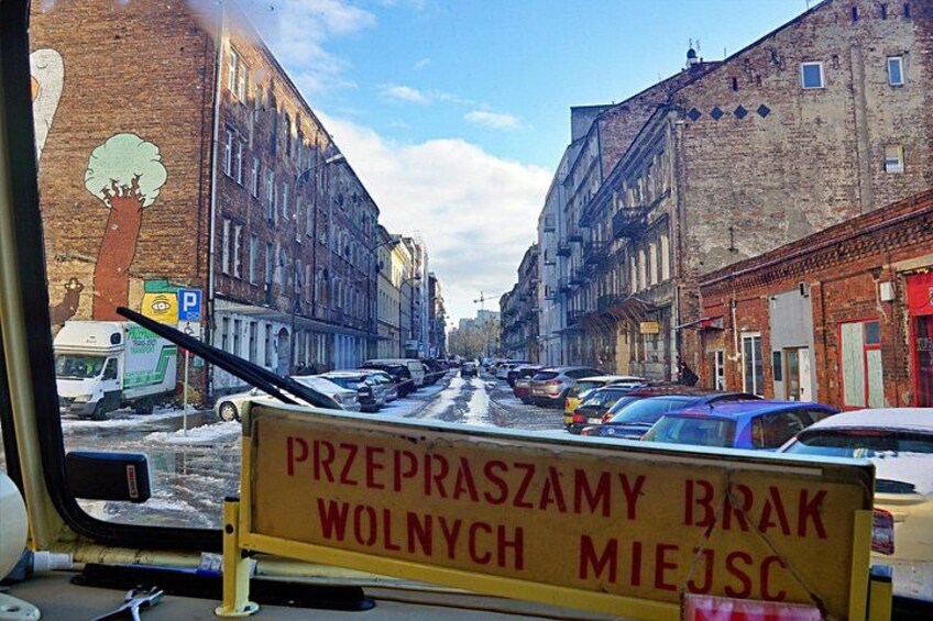 Una vista di una strada con auto parcheggiate, edifici e un cartello in lingua straniera. 2