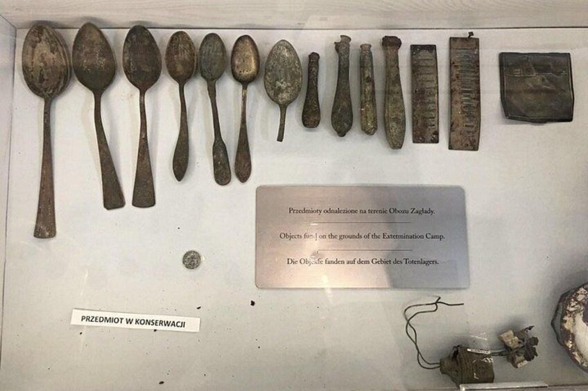 Eine Sammlung historischer Artefakte, darunter Löffel und eine Geldbörse, präsentiert in einer Museums-Vitrine. 2