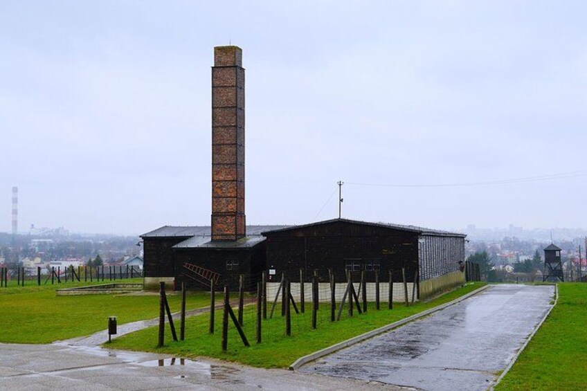 Un grand bâtiment industriel, doté d’une haute cheminée, entouré d’une zone herbeuse et d’un chemin pavé. 2