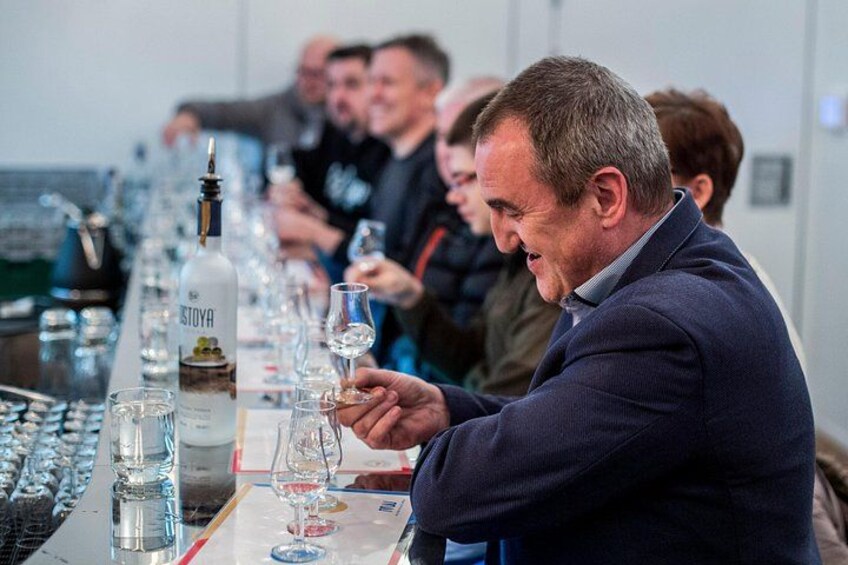 Een man houdt een wijnglas vast tijdens een proeverij, met flessen en glazen op tafel. 2