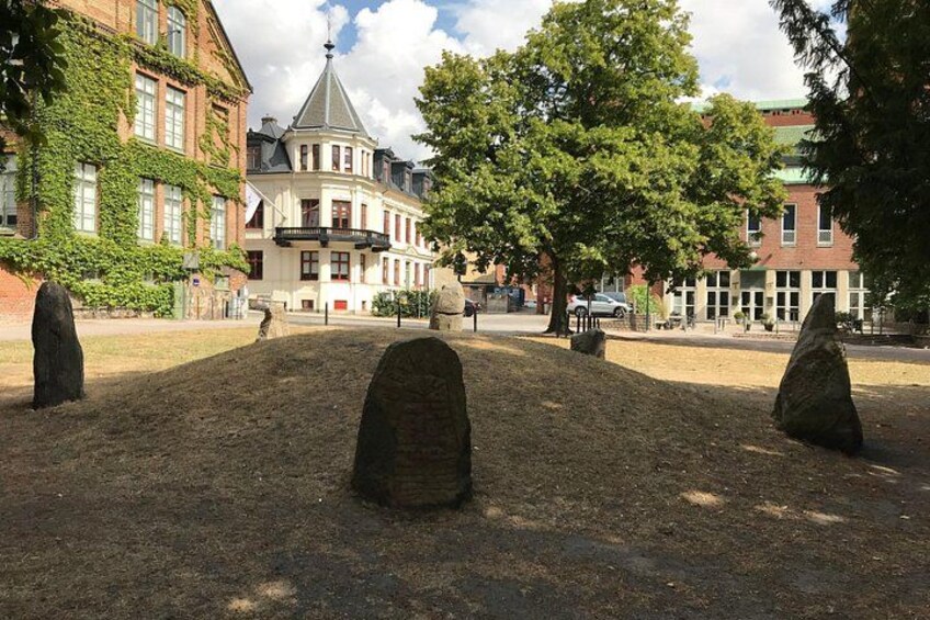 A park with three stone sculptures, a building with a turret, and trees. 2
