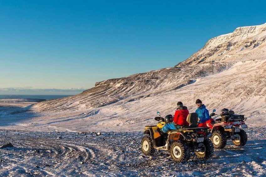 A group of people on an ATV in a snowy landscape with a clear sky. 4