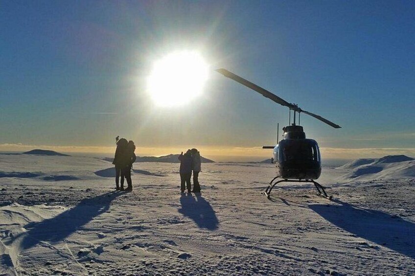 A helicopter on a snowy landscape with the sun in the background. 3