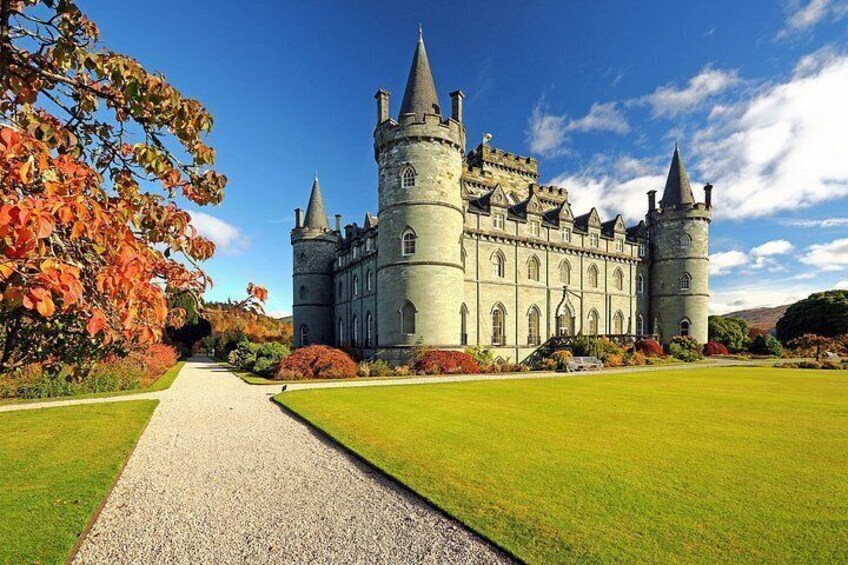 A castle with turrets, a gravel path, and autumn foliage. 3
