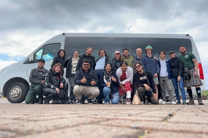 Un grupo de personas posando frente a una furgoneta blanca. 3