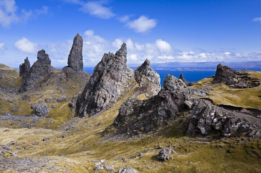 A rugged landscape with prominent rocky formations and a distant view of the ocean under a clear sky. 1