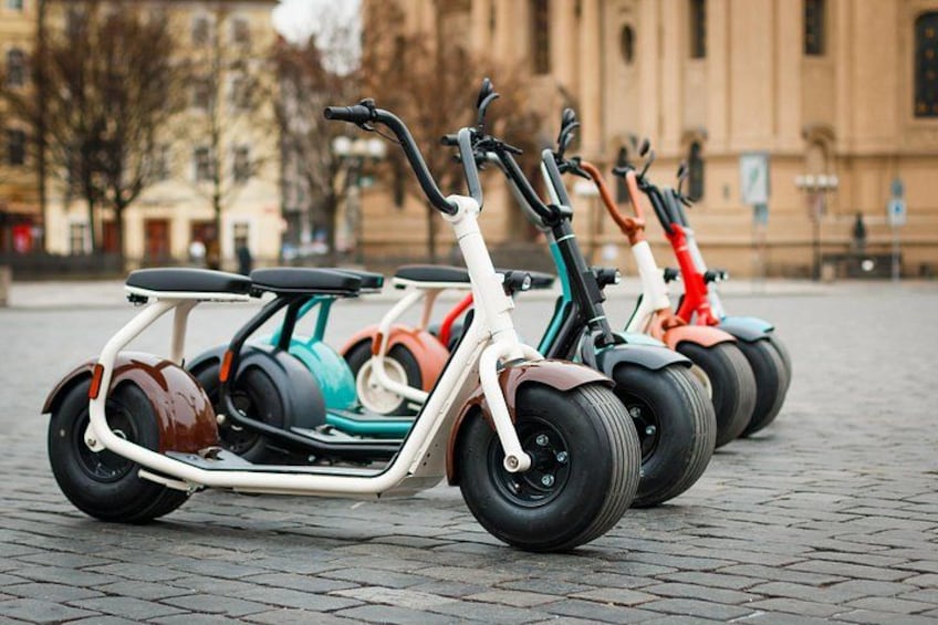 A row of electric scooters parked on a cobblestone street. 5