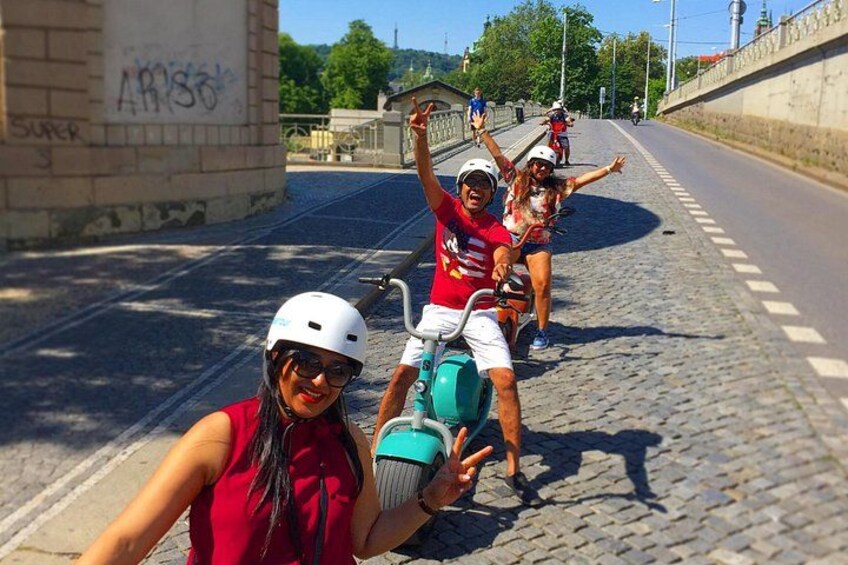 A group of people on a cobblestone street, some wearing helmets and holding water bottles. 3