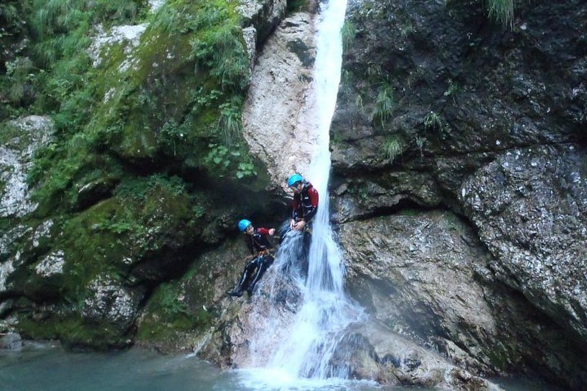 A person rappelling down a waterfall surrounded by rocky terrain and greenery. 4