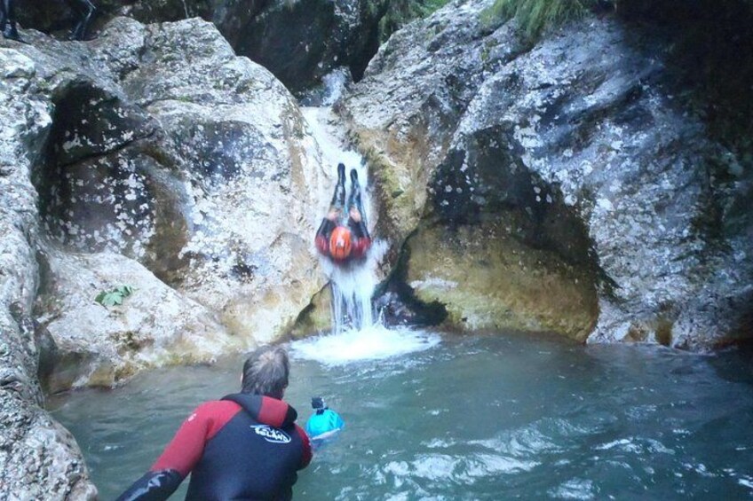 A person in a wetsuit taking a photograph of a waterfall. 5